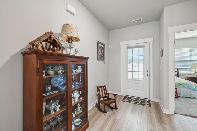doorway with visible vents, light wood-style flooring, and baseboards