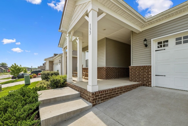 doorway to property with brick siding, a garage, and a porch