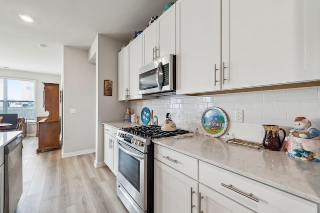 kitchen with light stone countertops, baseboards, white cabinetry, tasteful backsplash, and appliances with stainless steel finishes