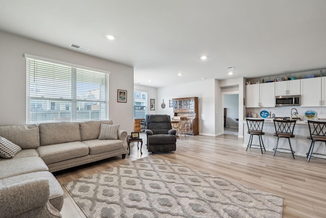 living area with recessed lighting, baseboards, visible vents, and light wood-style floors