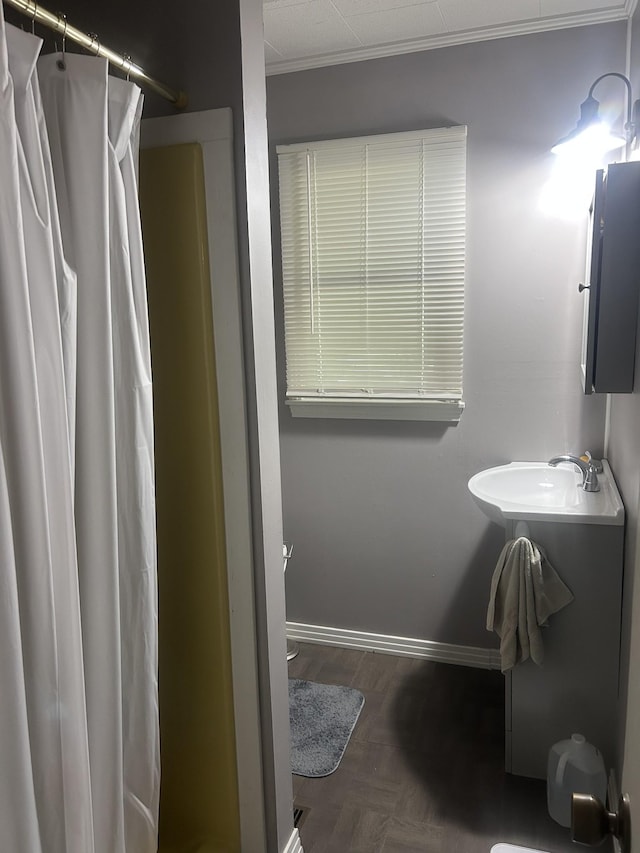 bathroom with ornamental molding, curtained shower, toilet, baseboards, and a sink