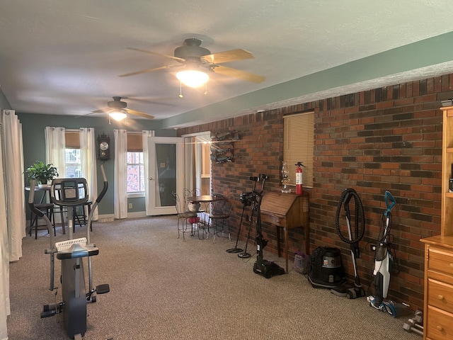 misc room with carpet floors, a ceiling fan, baseboards, and brick wall