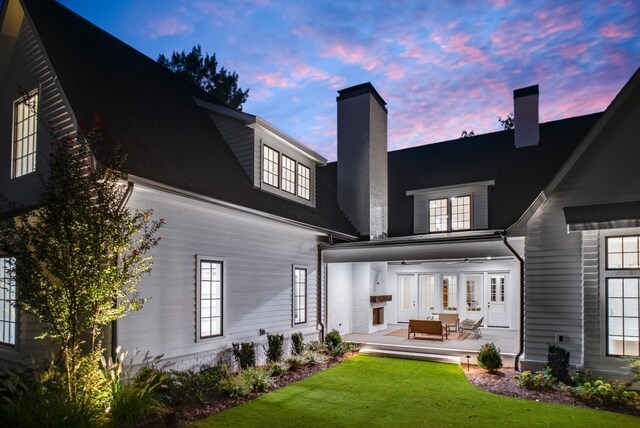 1105 Brookmeade Dr, Nashville, TN 37204 - back of house at dusk with french doors, a chimney, a lawn, an outdoor hangout area, and a patio