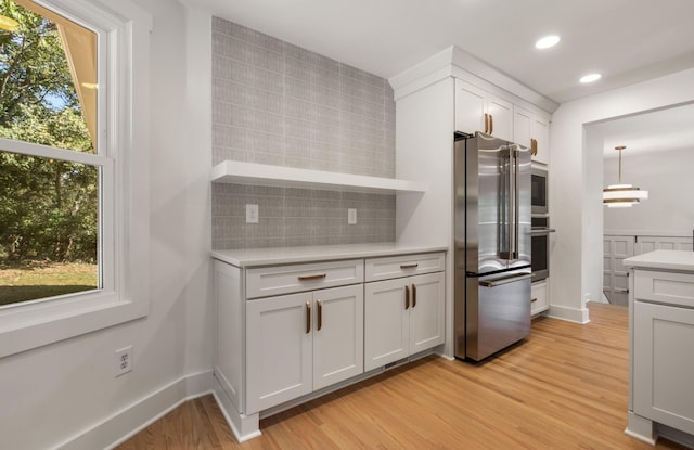 6556 Jocelyn Hollow Rd, Nashville, TN 37205 - kitchen featuring white cabinets, appliances with stainless steel finishes, light countertops, light wood-style flooring, and backsplash