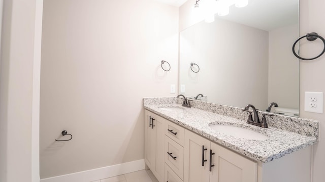 bathroom featuring double vanity, baseboards, a sink, and tile patterned floors