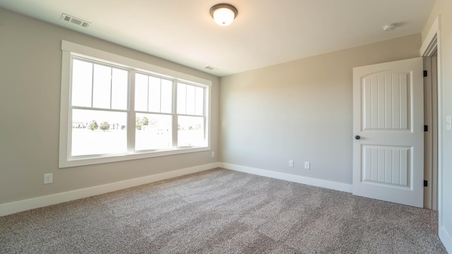 empty room featuring carpet floors, baseboards, and visible vents