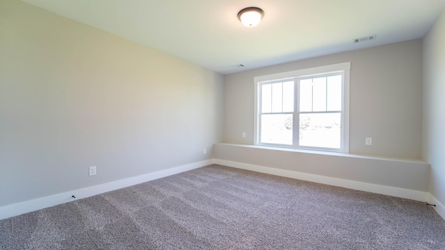 carpeted spare room featuring baseboards and visible vents