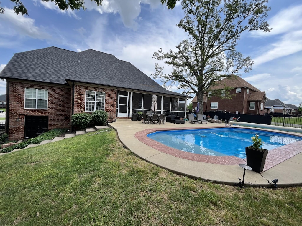 view of swimming pool with fence, a patio, a sunroom, a fenced in pool, and a lawn