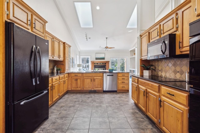 1403 Sneed Rd W, Franklin, TN 37069 - kitchen featuring a peninsula, dark countertops, vaulted ceiling with skylight, tasteful backsplash, and black appliances
