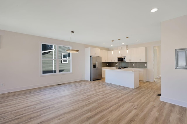 kitchen featuring stainless steel appliances, tasteful backsplash, light countertops, white cabinetry, and light wood-type flooring