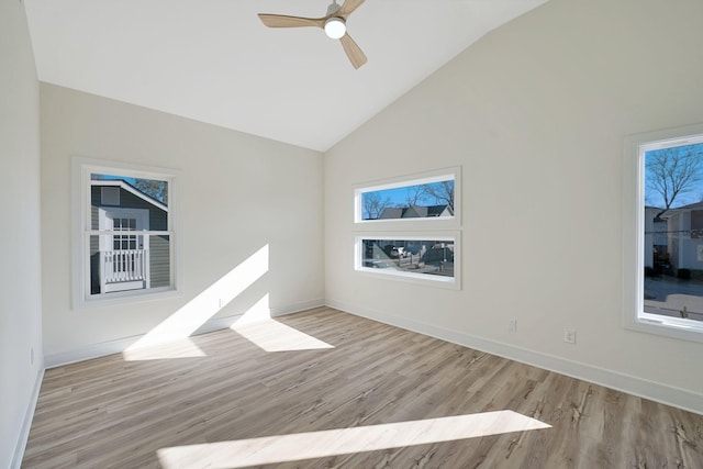 spare room featuring vaulted ceiling, light wood finished floors, baseboards, and a ceiling fan