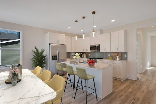 kitchen featuring appliances with stainless steel finishes, decorative backsplash, white cabinets, a kitchen breakfast bar, and recessed lighting