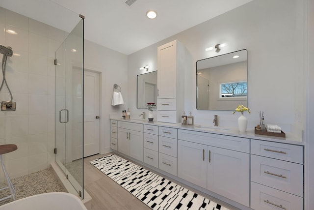 full bathroom featuring a stall shower, double vanity, a freestanding bath, and recessed lighting