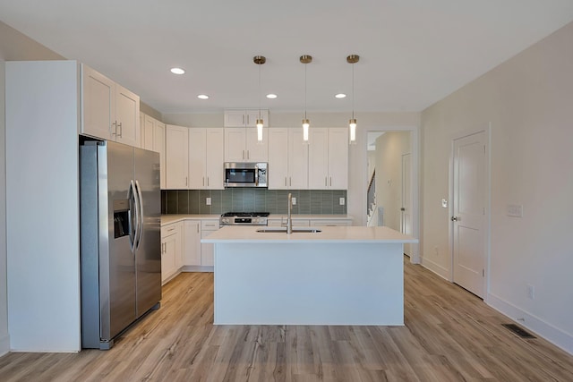 kitchen with appliances with stainless steel finishes, a sink, backsplash, light wood-style floors, and light countertops