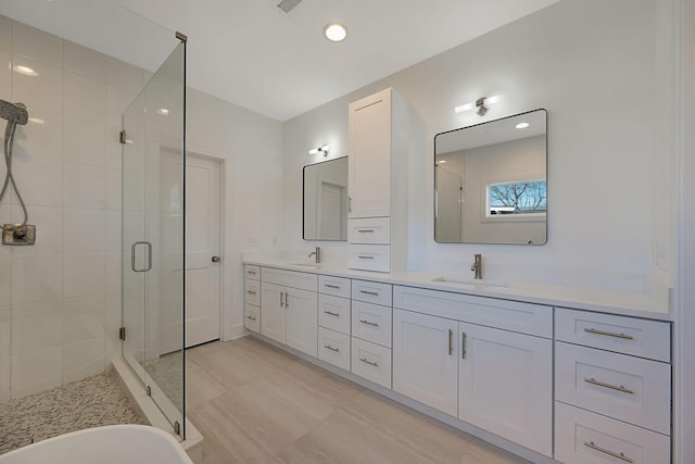 full bath with a shower stall, double vanity, a soaking tub, and recessed lighting