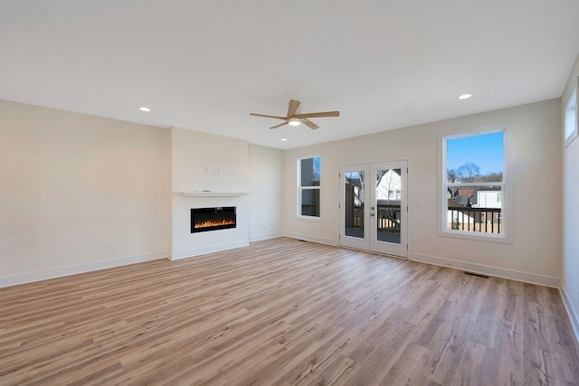unfurnished living room featuring ceiling fan, light wood-style floors, baseboards, a lit fireplace, and recessed lighting