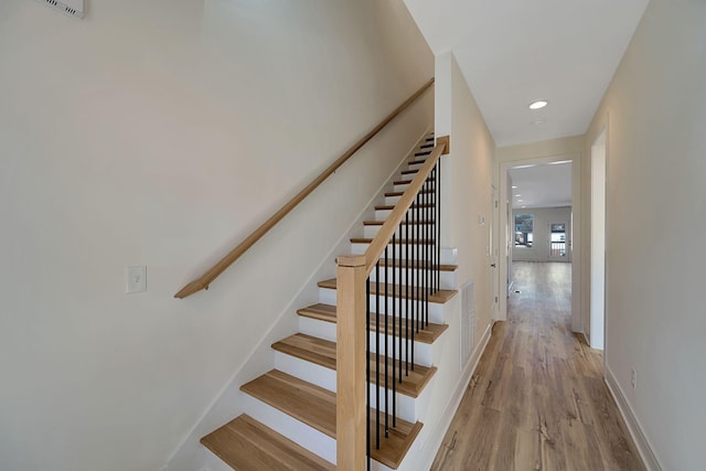stairway with wood finished floors, baseboards, and recessed lighting