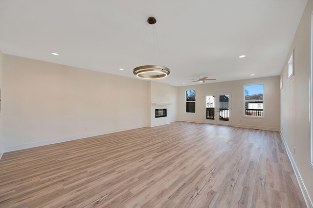 unfurnished living room featuring light wood-style floors, baseboards, a ceiling fan, recessed lighting, and a glass covered fireplace