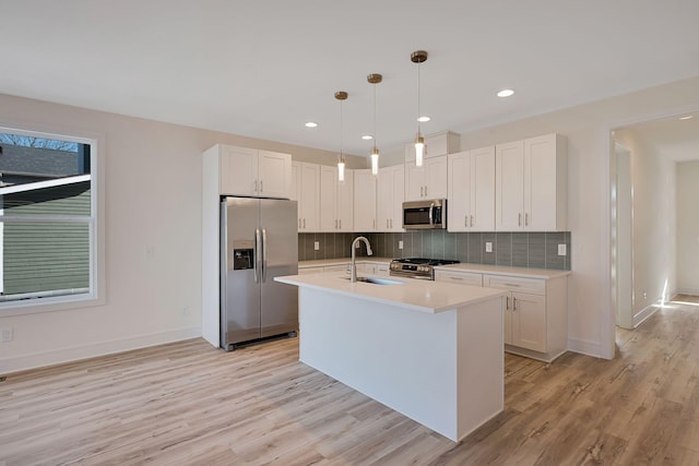 kitchen featuring appliances with stainless steel finishes, a sink, light wood finished floors, light countertops, and decorative backsplash