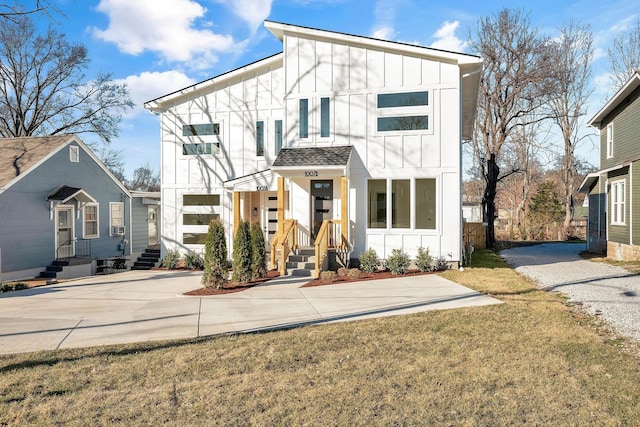 contemporary home featuring board and batten siding, a shingled roof, and a front lawn