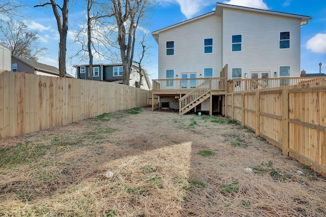 back of property with a fenced backyard, stairway, and a deck