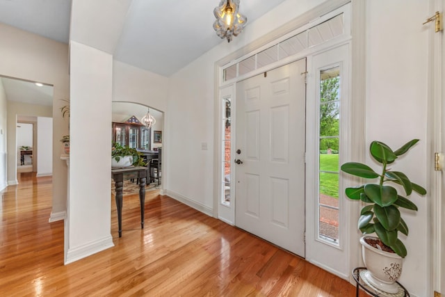 entryway featuring baseboards, a notable chandelier, and light wood finished floors