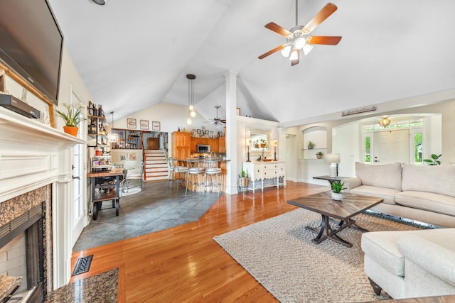 living room with wood finished floors, a ceiling fan, lofted ceiling, and a premium fireplace