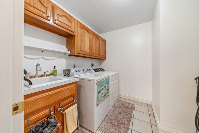 laundry area with washing machine and dryer, cabinet space, a sink, baseboards, and light tile patterned flooring