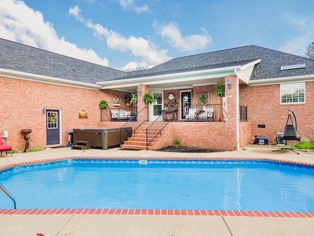 outdoor pool with a hot tub and a patio area