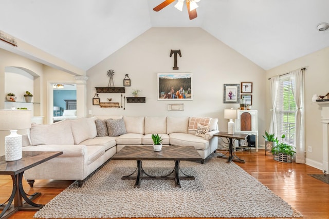 living room with decorative columns, wood finished floors, baseboards, ceiling fan, and vaulted ceiling