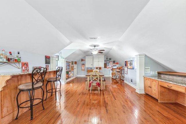 interior space with a ceiling fan, visible vents, a bar, light wood finished floors, and lofted ceiling