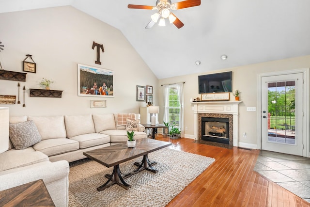 living room featuring a fireplace with flush hearth, high vaulted ceiling, a ceiling fan, and hardwood / wood-style flooring