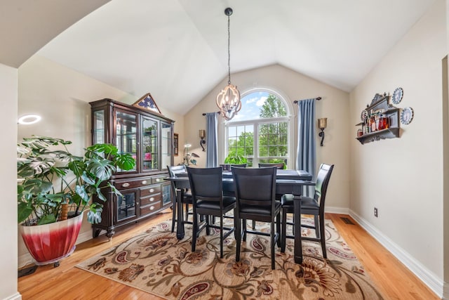 dining area with an inviting chandelier, light wood-style flooring, baseboards, vaulted ceiling, and visible vents