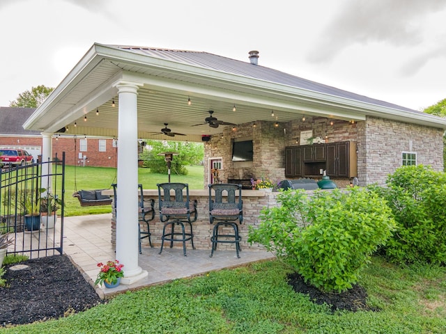 view of patio featuring a ceiling fan, fence, and outdoor dry bar