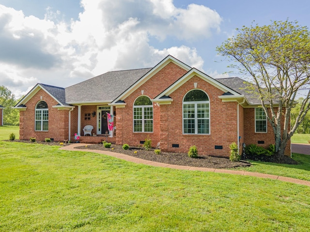 ranch-style home featuring brick siding, roof with shingles, a front yard, and crawl space