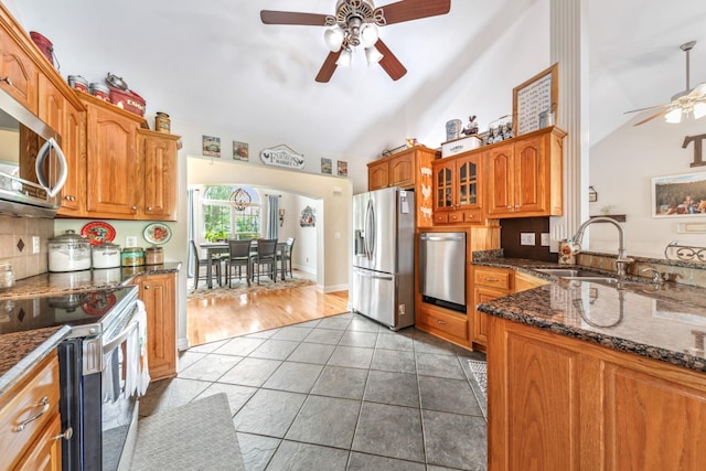 kitchen featuring brown cabinets, a sink, tile patterned flooring, stainless steel appliances, and a ceiling fan