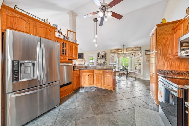 kitchen featuring a sink, stainless steel appliances, a ceiling fan, a peninsula, and vaulted ceiling