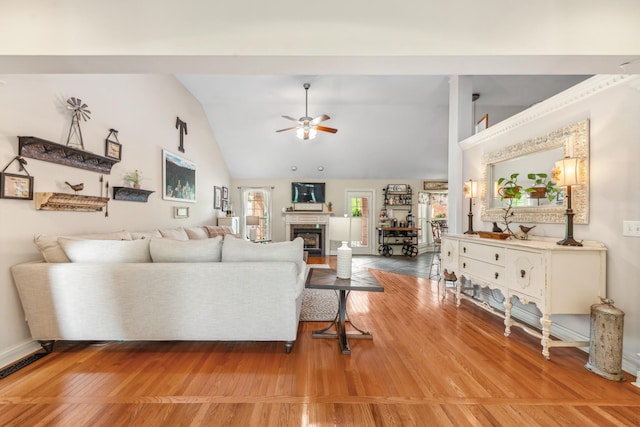 living room with ceiling fan, a glass covered fireplace, wood finished floors, and lofted ceiling
