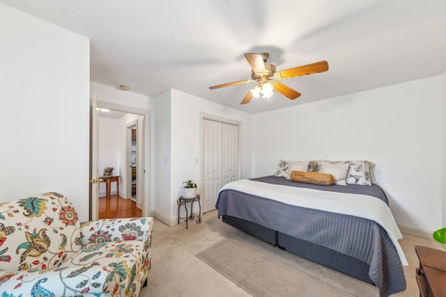 bedroom featuring ceiling fan, light carpet, baseboards, and a closet