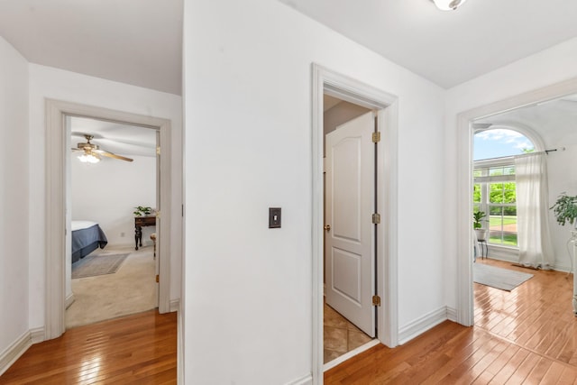 corridor featuring baseboards and light wood finished floors