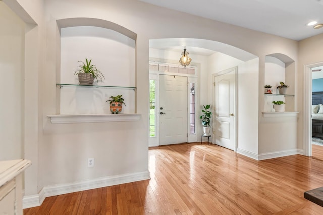 foyer entrance with arched walkways, baseboards, recessed lighting, and wood finished floors