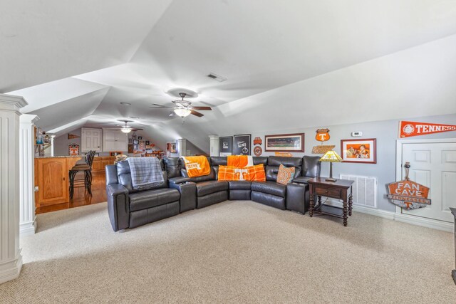 living area with decorative columns, a ceiling fan, visible vents, vaulted ceiling, and light carpet