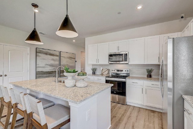kitchen featuring visible vents, decorative backsplash, white cabinets, light wood-style flooring, and stainless steel appliances