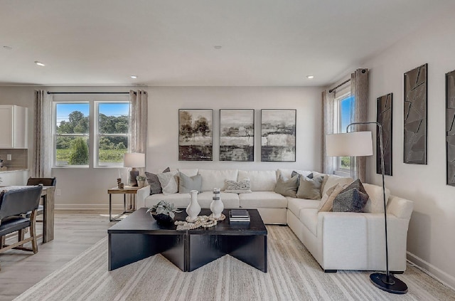 living area featuring recessed lighting, baseboards, light wood finished floors, and a wealth of natural light