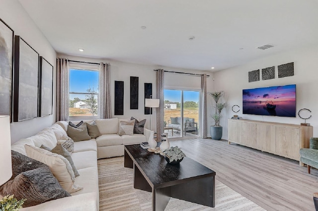 living area with recessed lighting, visible vents, a healthy amount of sunlight, and light wood-style floors