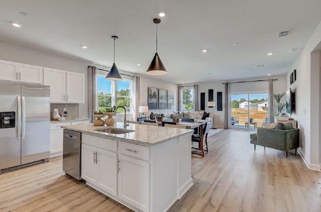 kitchen featuring stainless steel appliances, open floor plan, a sink, and light wood finished floors