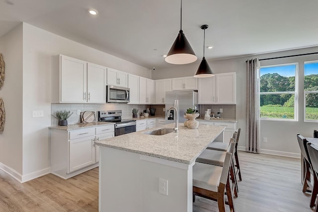 kitchen featuring a sink, baseboards, stainless steel appliances, and light wood-style flooring
