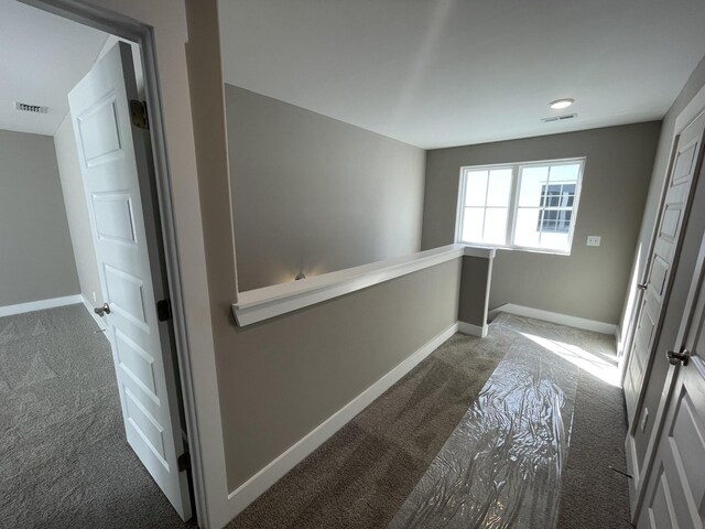 hall featuring carpet floors, baseboards, and visible vents