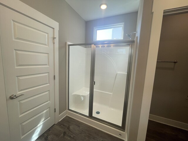 full bathroom with baseboards, wood finished floors, and a shower stall