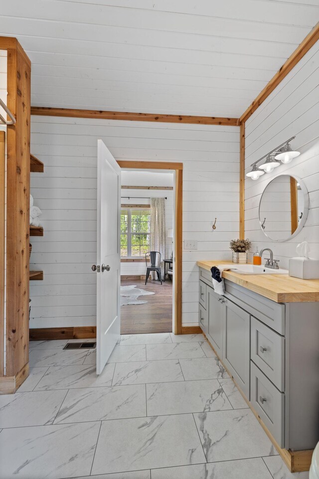 bathroom featuring visible vents, marble finish floor, wooden walls, and vanity